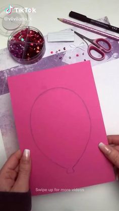 someone is making a heart shaped card out of paper and crafting it with scissors