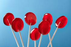 red candy lollipops are on sticks against a blue sky