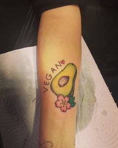 an avocado tattoo on the arm with flowers and words written in cursive writing