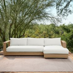 a white couch sitting on top of a wooden floor next to a tree filled forest