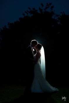 a bride and groom kissing in the dark