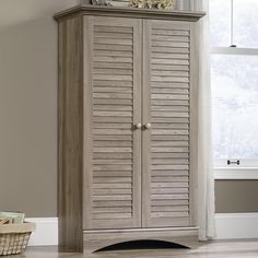 a wooden cabinet with shutters on the top and bottom, in front of a window