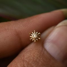 a person's hand holding a tiny gold ring with a diamond in the middle