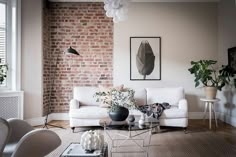 a living room filled with furniture and a brick wall behind the couch is a potted plant