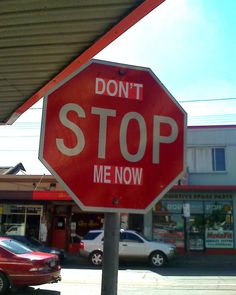 a red stop sign sitting on the side of a road next to a parking lot