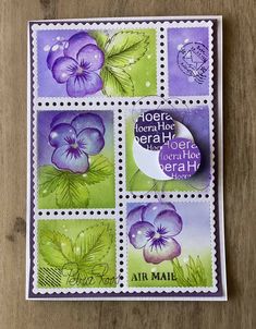 a stamp with purple flowers and green leaves on the front, sitting on top of a wooden table