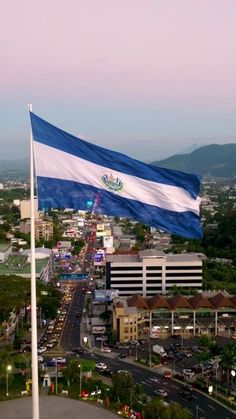 an aerial view of a city with a flag in the foreground and mountains in the background