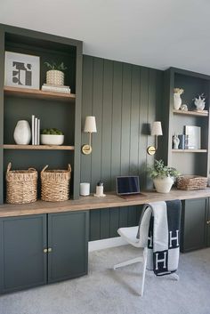 a home office with green painted walls and shelves