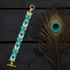 a peacock feather resting next to a blue and white beaded key fobl