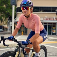 a woman riding on the back of a bike down a street