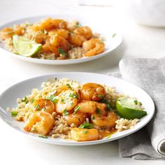 two white plates filled with shrimp and rice on top of a table next to a napkin