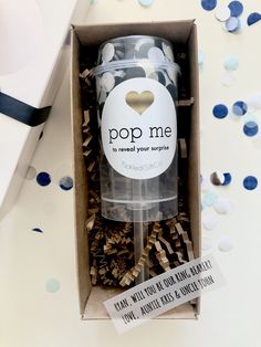 an open box with some confetti in it and the lid is white, gold and black