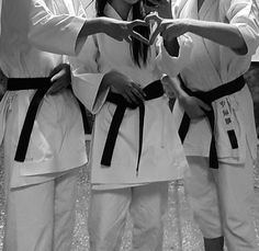 three women in karate uniforms holding their hands together