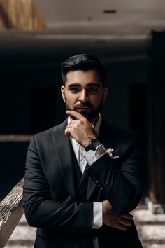 a man in a suit and tie leaning on a bench with his hand under his chin