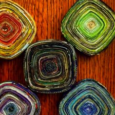 four colorful glass coasters sitting on top of a wooden table next to each other