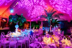 a large tent with tables and chairs set up for a formal dinner or function in the evening