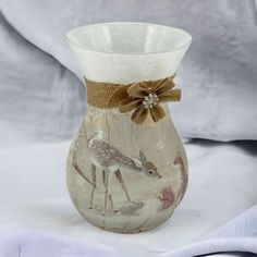 a glass vase decorated with deers and flowers on a white tableclothed background