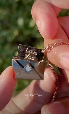 someone is holding a tiny origami love you message on a chain that says i love you