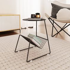 two chairs and a table with magazines on it in a living room next to a window