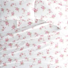 a bed with white sheets and pink flowers on it