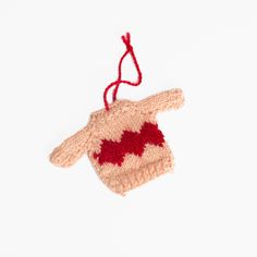 a knitted mitten ornament hanging from a string on a white background