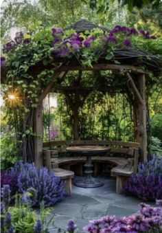 a wooden gazebo surrounded by purple flowers and greenery