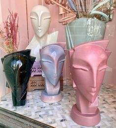 several vases are sitting on a table in front of a mirror, one is pink and the other is blue