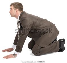 a man in a suit and tie kneeling on the ground with his hands behind his back