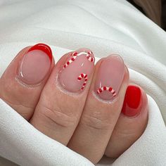 A subtle nod to the holiday season, this design features a clear nude base with candy cane details on just the tips. The candy cane pattern gracefully arches around the edge, creating a minimalist yet festive look. Bright red accent nails complement the simple design, adding a pop of color that’s both modern and chic. Chrimbo Nails, Candy Cain Nails, Candy Cane Nails Short, Red Accent Nails, Christmas Gel Manicure, Candy Cane Nail Designs, Candy Cane Christmas Nails, Candy Cane Nail Art, Candy Cane Nail