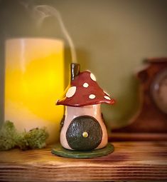 a small mushroom house sitting on top of a table next to a glass of beer