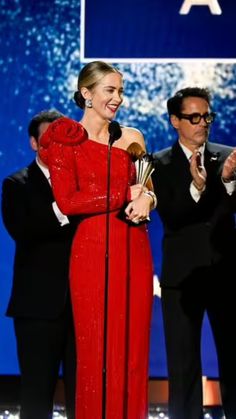 a woman in a red dress holding an award