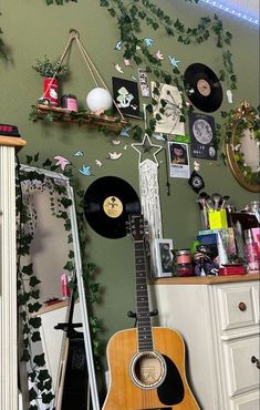 an acoustic guitar sitting on top of a table next to a wall covered in pictures