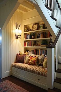 a bookshelf filled with lots of books next to a stair case in a home