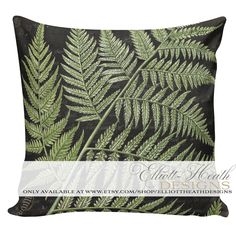 a black and green pillow with fern leaves on it