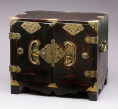 an old wooden cabinet with gold decorations on the front and sides, sitting against a white background