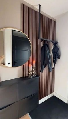 a room with a mirror, coat rack and two candles on the dresser next to it