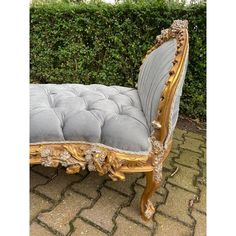 an ornately decorated bench sitting in front of a hedge covered with shrubbery and stone pavers