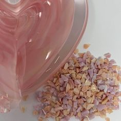 a pink heart shaped bowl next to a pile of nuts