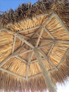 an umbrella made out of straw and wood with blue sky in the backgroud