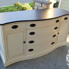 an old dresser is painted white and has black knobs on the top, and bottom