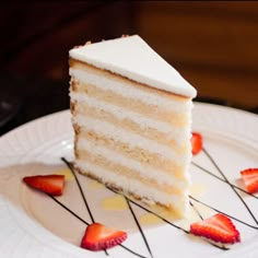 a slice of white cake with strawberries on the side sits on a plate, ready to be eaten