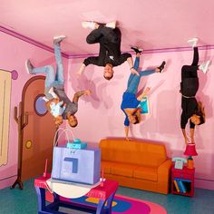 three people are upside down on the floor in a room with pink walls and furniture