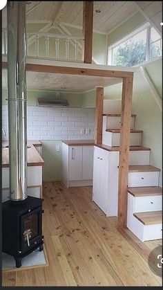 an empty room with wood floors and white cabinets in the center, stairs leading up to the second floor