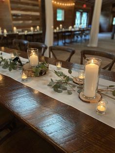 a long table with candles and greenery on it