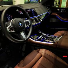 the interior of a bmw car with brown leather seats and steering wheel, illuminated by blue lights