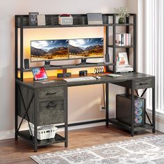 a desk with a computer on it in front of a window and a rug next to it