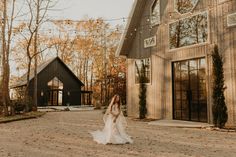 a woman standing in front of a barn wearing a white wedding dress and long veil