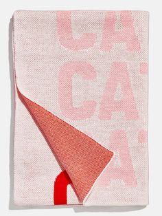 a pink and red blanket with the word coach on it's side, folded in half