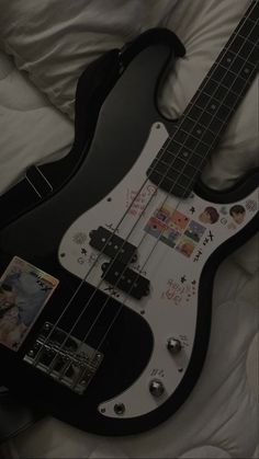 a black and white electric guitar laying on top of a bed next to an mp3 player