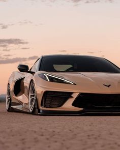 a white sports car parked in the middle of a dirt field at sunset or dawn